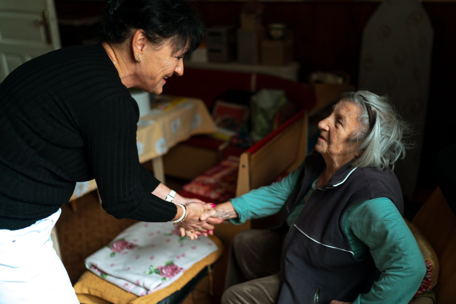 An older woman greeting a visitor in her home