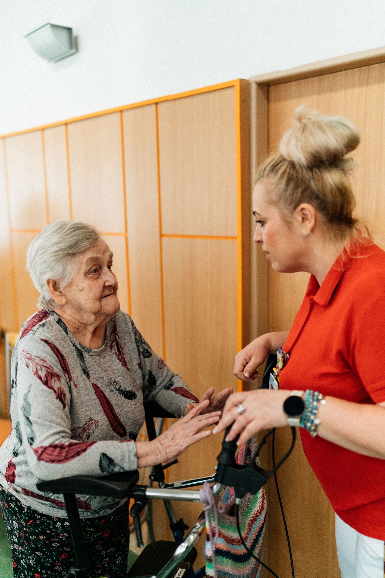 A caregiver talking with an older woman beside her walker