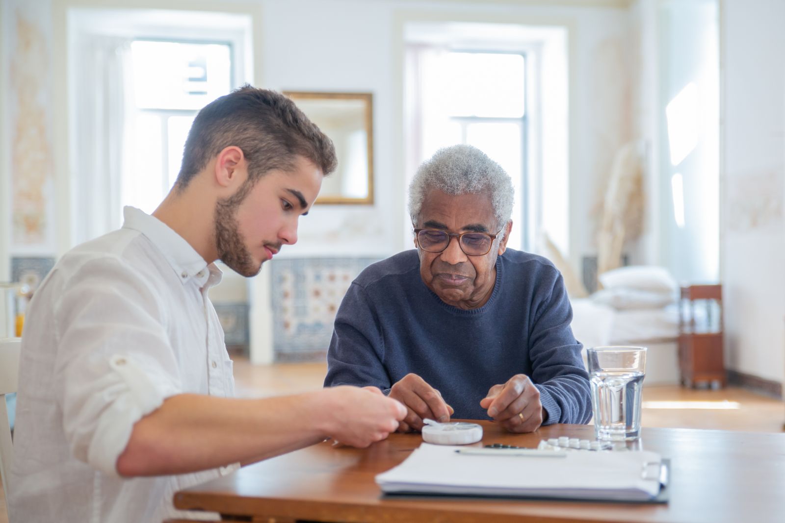 A caregiver helping an older man organize his medication at home